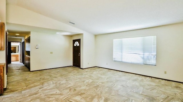 empty room featuring baseboards, visible vents, and vaulted ceiling