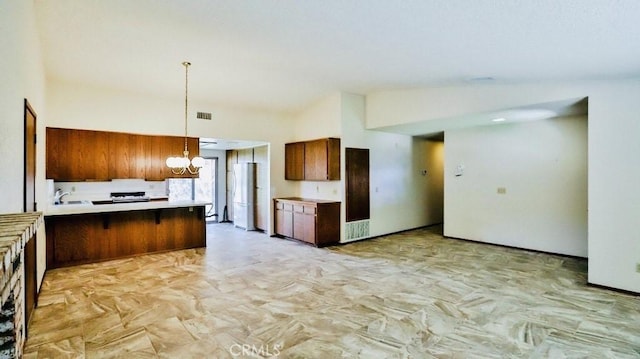 kitchen with brown cabinetry, a breakfast bar, freestanding refrigerator, a peninsula, and light countertops