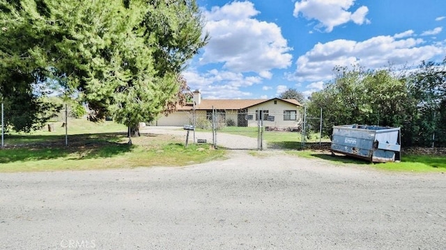 view of front of property featuring a chimney, a gate, fence, and driveway