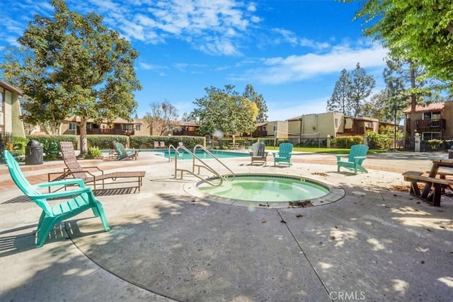 community pool with a hot tub, a residential view, fence, and a patio