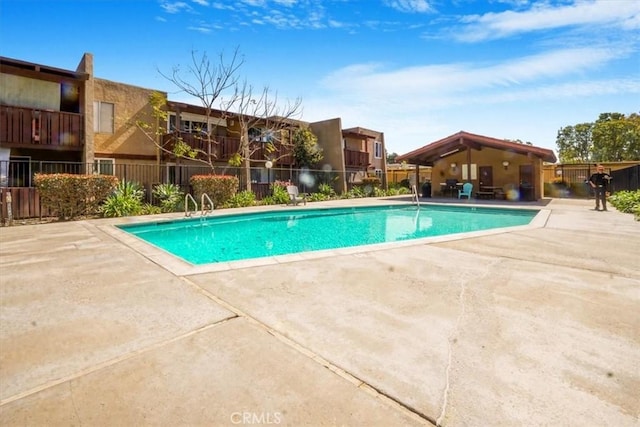 community pool with a patio and fence