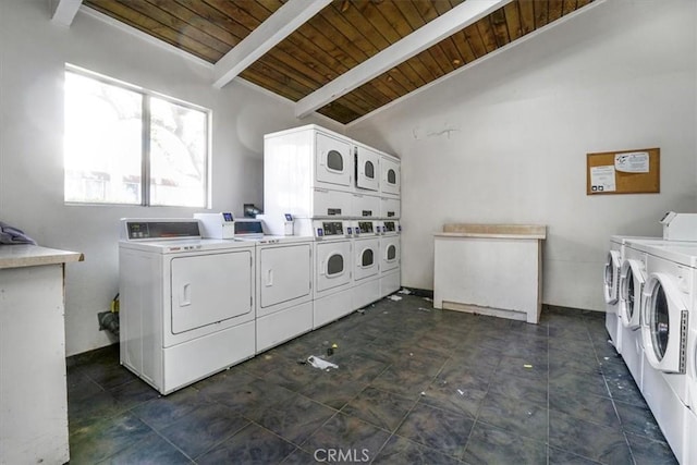 shared laundry area featuring stacked washer and dryer, wooden ceiling, washing machine and dryer, and baseboards