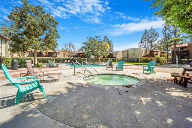 pool with a patio area, a hot tub, a residential view, and fence