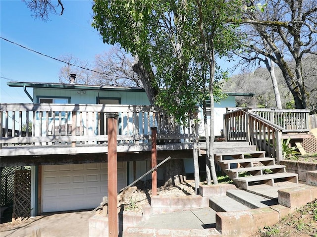 rear view of house featuring a garage, stairway, and a wooden deck