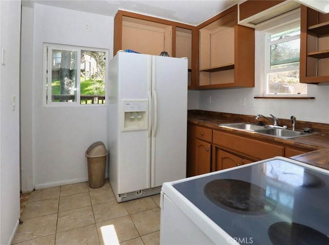 kitchen featuring white appliances, light tile patterned floors, dark countertops, open shelves, and a sink