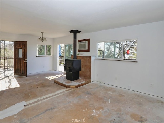 unfurnished living room with a wood stove and a wall unit AC