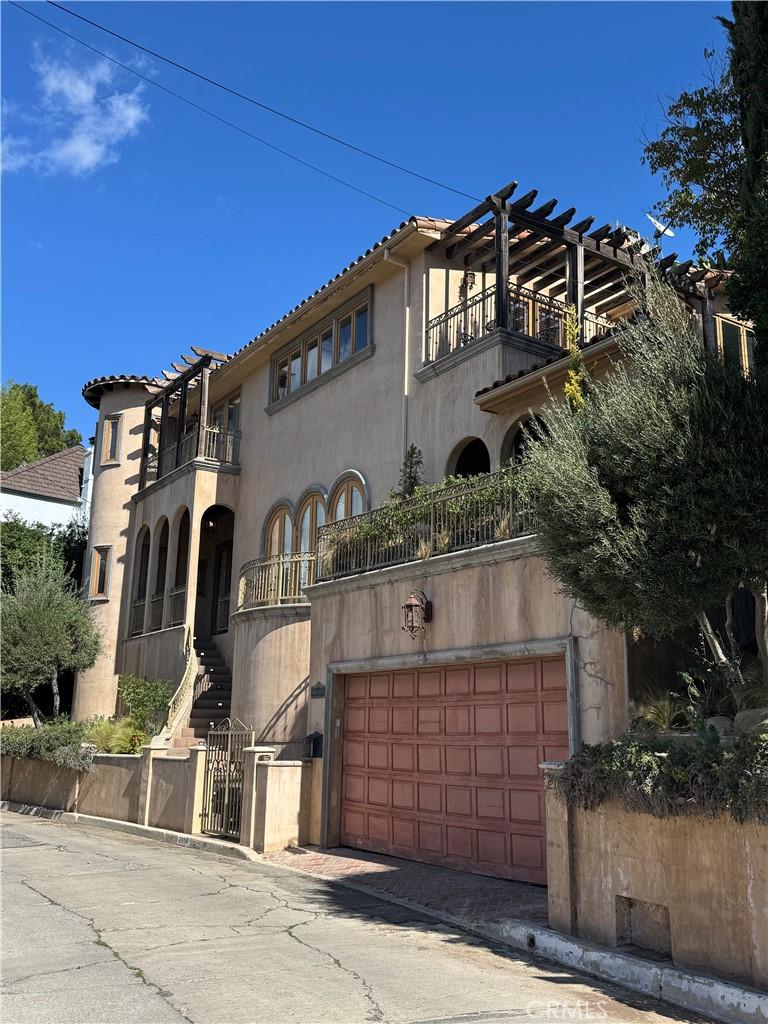 mediterranean / spanish-style home featuring a garage, a balcony, and stucco siding