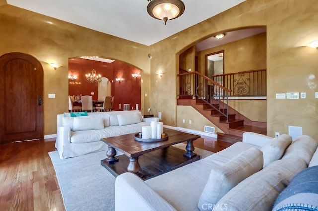 living area featuring baseboards, visible vents, arched walkways, stairway, and wood finished floors