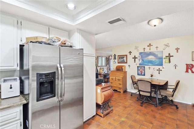 kitchen featuring stainless steel refrigerator with ice dispenser, a raised ceiling, visible vents, and white cabinets