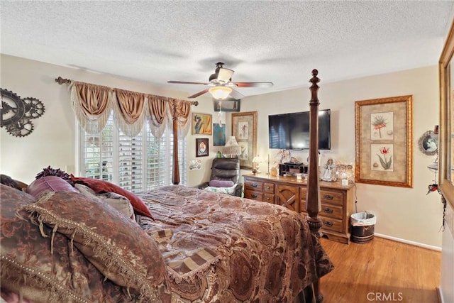 bedroom featuring a textured ceiling, wood finished floors, a ceiling fan, and baseboards