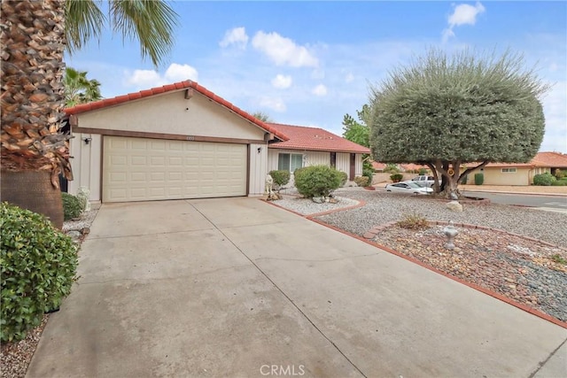 view of front of home with a garage, a tile roof, driveway, and stucco siding