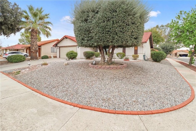 view of front facade with a tile roof, driveway, an attached garage, and stucco siding