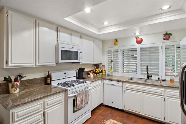 kitchen featuring a tray ceiling, white appliances, a sink, and white cabinets