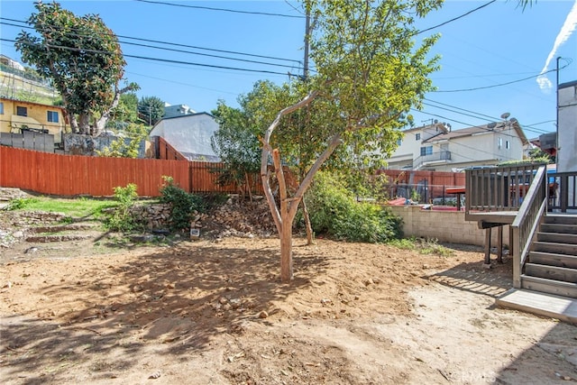 view of yard with a fenced backyard, a wooden deck, and stairs