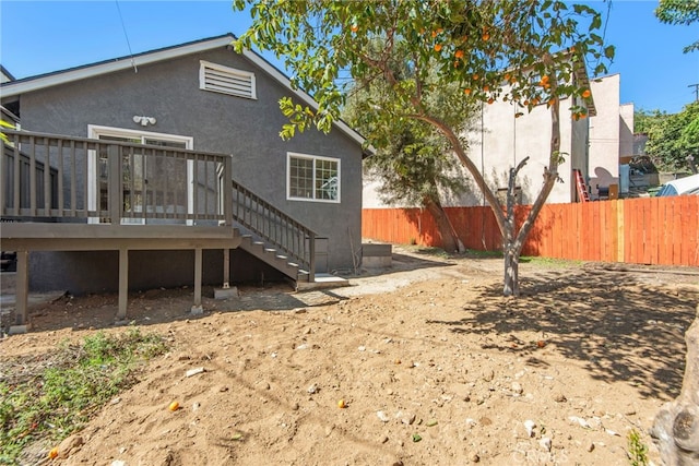 back of house featuring a deck, fence, stairs, and stucco siding