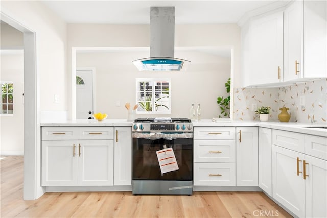 kitchen with island range hood, light countertops, backsplash, and gas stove