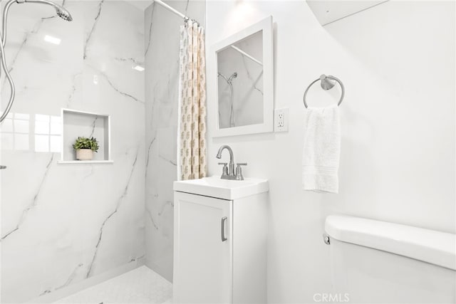 bathroom featuring toilet, a marble finish shower, and vanity