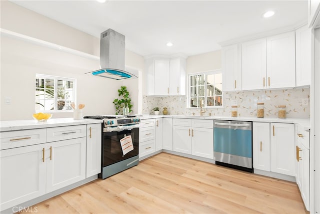 kitchen with island exhaust hood, decorative backsplash, appliances with stainless steel finishes, light wood-style floors, and white cabinets