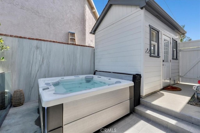 view of patio with a gate, a hot tub, and fence