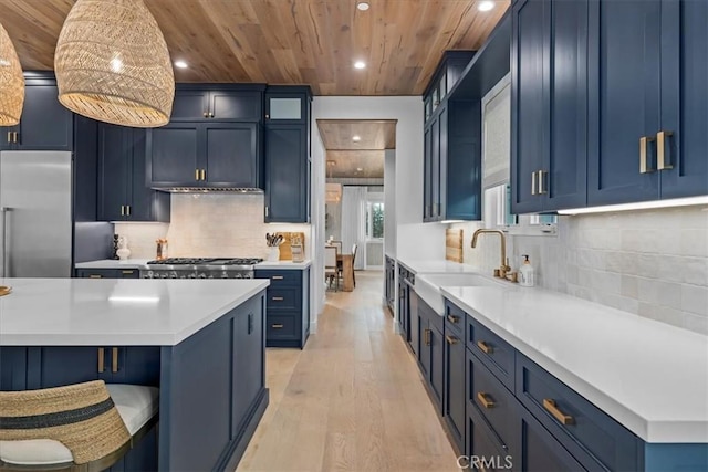 kitchen with a sink, light countertops, appliances with stainless steel finishes, wooden ceiling, and blue cabinets