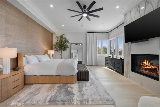 bedroom featuring recessed lighting, a large fireplace, and light wood-style flooring