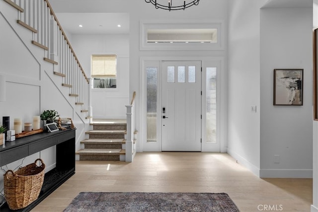 entryway with wood finished floors, recessed lighting, baseboards, a towering ceiling, and stairs