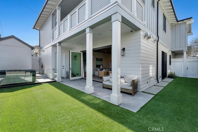 rear view of house featuring board and batten siding, fence, an outdoor hangout area, a yard, and a patio area