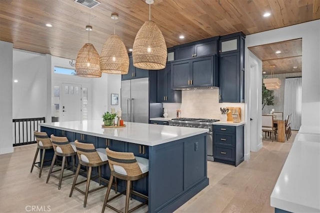 kitchen featuring light wood finished floors, a center island, high quality appliances, light countertops, and wooden ceiling