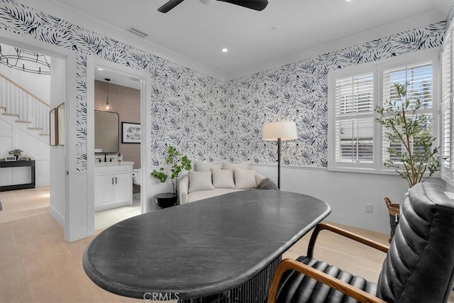 dining space with visible vents, wallpapered walls, ceiling fan, a wainscoted wall, and stairs