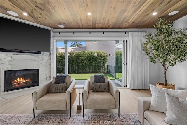 living room with a wealth of natural light, wood finished floors, wood ceiling, and a high end fireplace