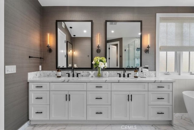 full bathroom with marble finish floor, a stall shower, and a sink