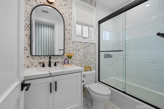 bathroom with vanity, enclosed tub / shower combo, tile walls, toilet, and tasteful backsplash