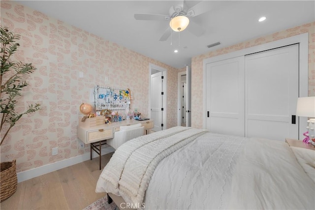 bedroom with visible vents, baseboards, wood finished floors, and wallpapered walls