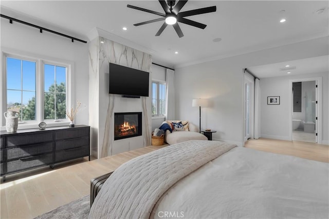 bedroom with a large fireplace, multiple windows, and light wood-style flooring