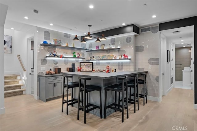 bar with recessed lighting, stairway, light wood-style floors, indoor wet bar, and decorative backsplash