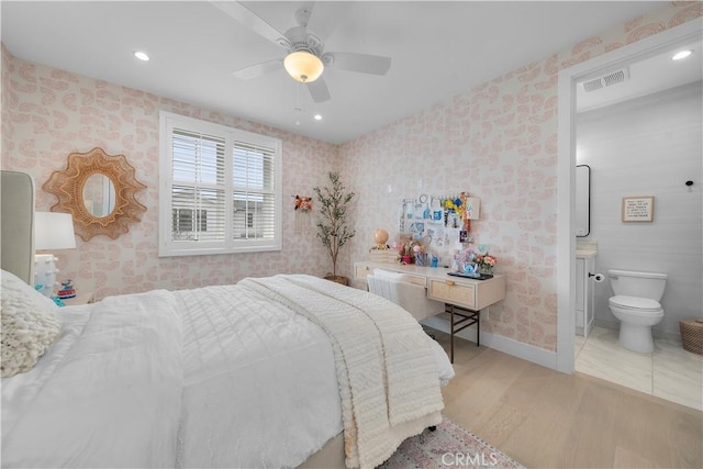 bedroom featuring visible vents, wallpapered walls, baseboards, light wood-type flooring, and ensuite bathroom