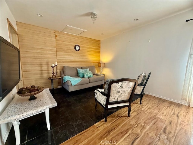 living room featuring attic access, wooden walls, baseboards, and wood finished floors