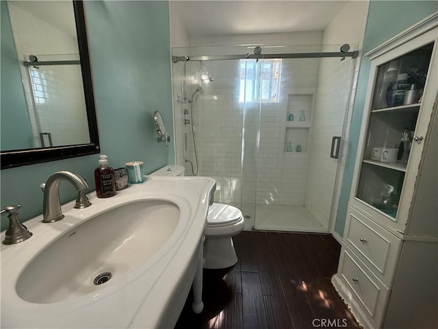 full bathroom featuring a sink, a shower stall, toilet, and wood finished floors