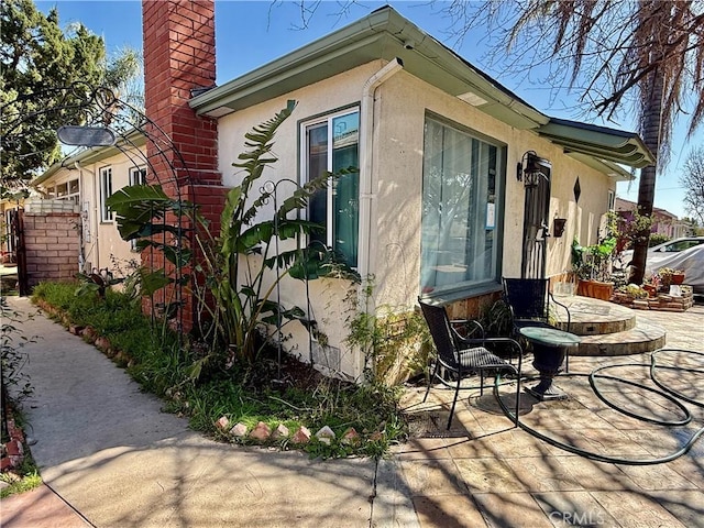 view of side of home with a chimney and stucco siding