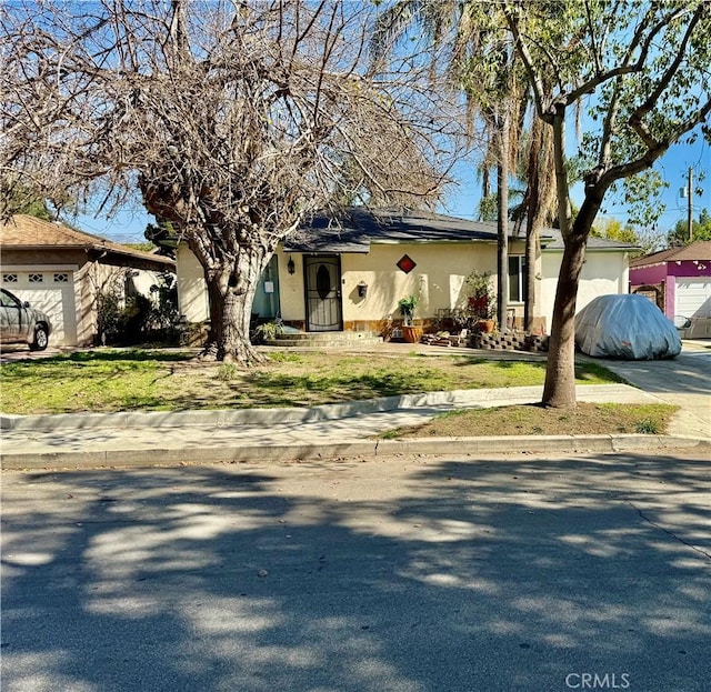 view of front facade with a garage, solar panels, a front yard, and stucco siding