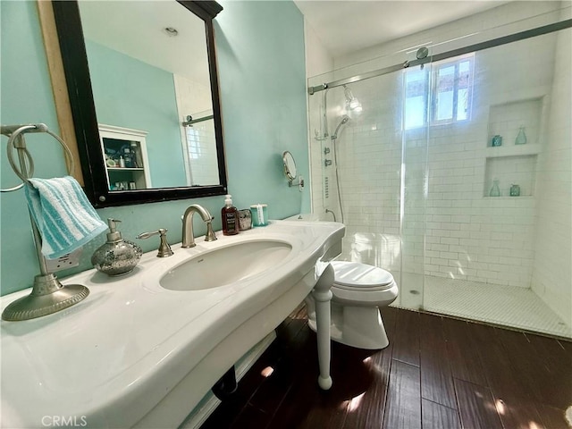 bathroom with a stall shower, a sink, toilet, and wood finished floors