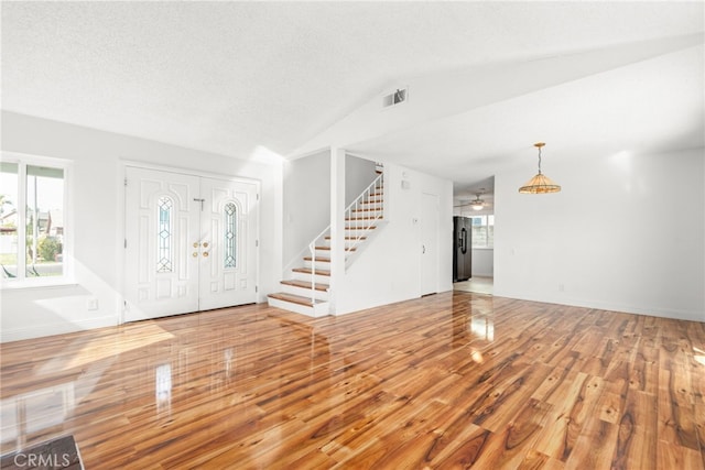 entrance foyer featuring visible vents, lofted ceiling, wood finished floors, stairs, and a wealth of natural light