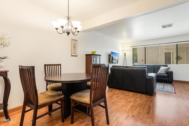 dining room featuring light wood-type flooring, baseboards, visible vents, and a chandelier