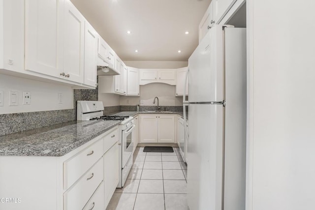 kitchen with white appliances, light stone counters, light tile patterned floors, a sink, and white cabinetry