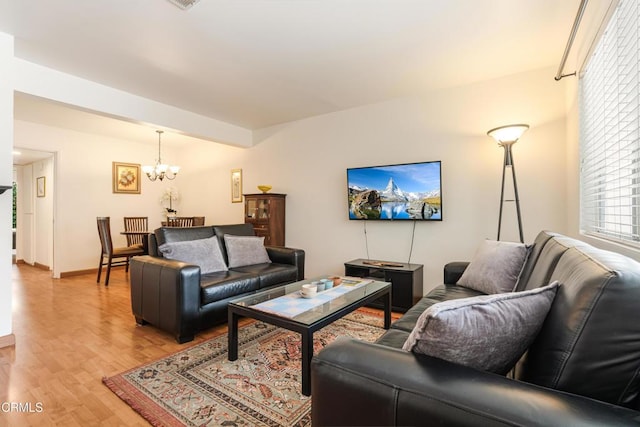 living room with baseboards, a chandelier, and light wood finished floors