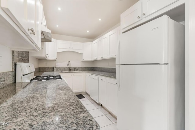 kitchen with white appliances, white cabinets, light stone counters, and a sink