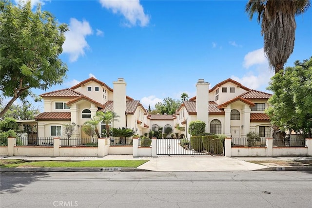 mediterranean / spanish house featuring a tiled roof, a fenced front yard, and stucco siding