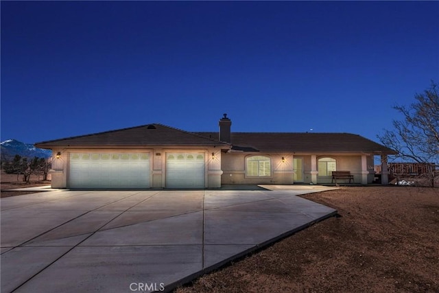 view of front facade featuring driveway, a tiled roof, an attached garage, and stucco siding