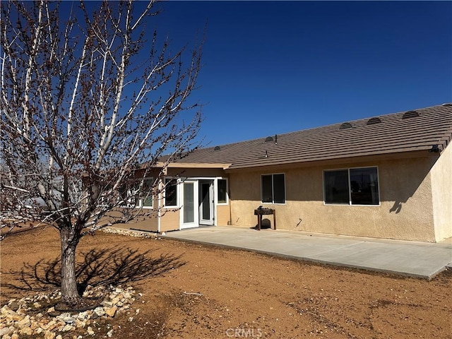 rear view of house featuring a patio area and stucco siding