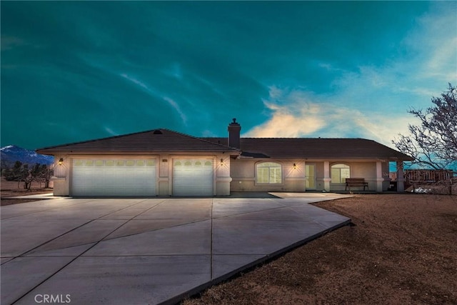 ranch-style home featuring an attached garage, driveway, a chimney, and stucco siding